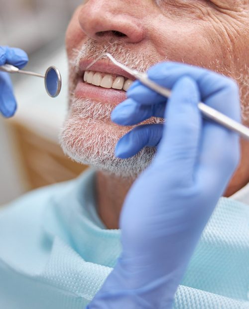 Cropped photo of a senior patient smiling while having his teeth examined